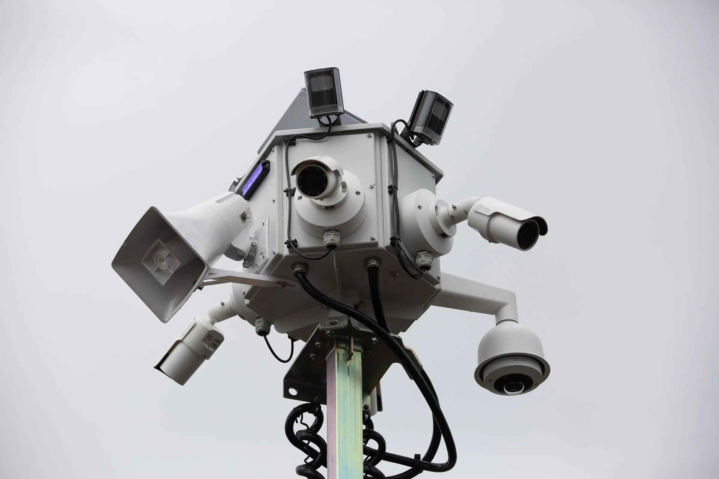Close-up of an Odin Systems mobile surveillance mast's multi-camera sensor head against an open sky