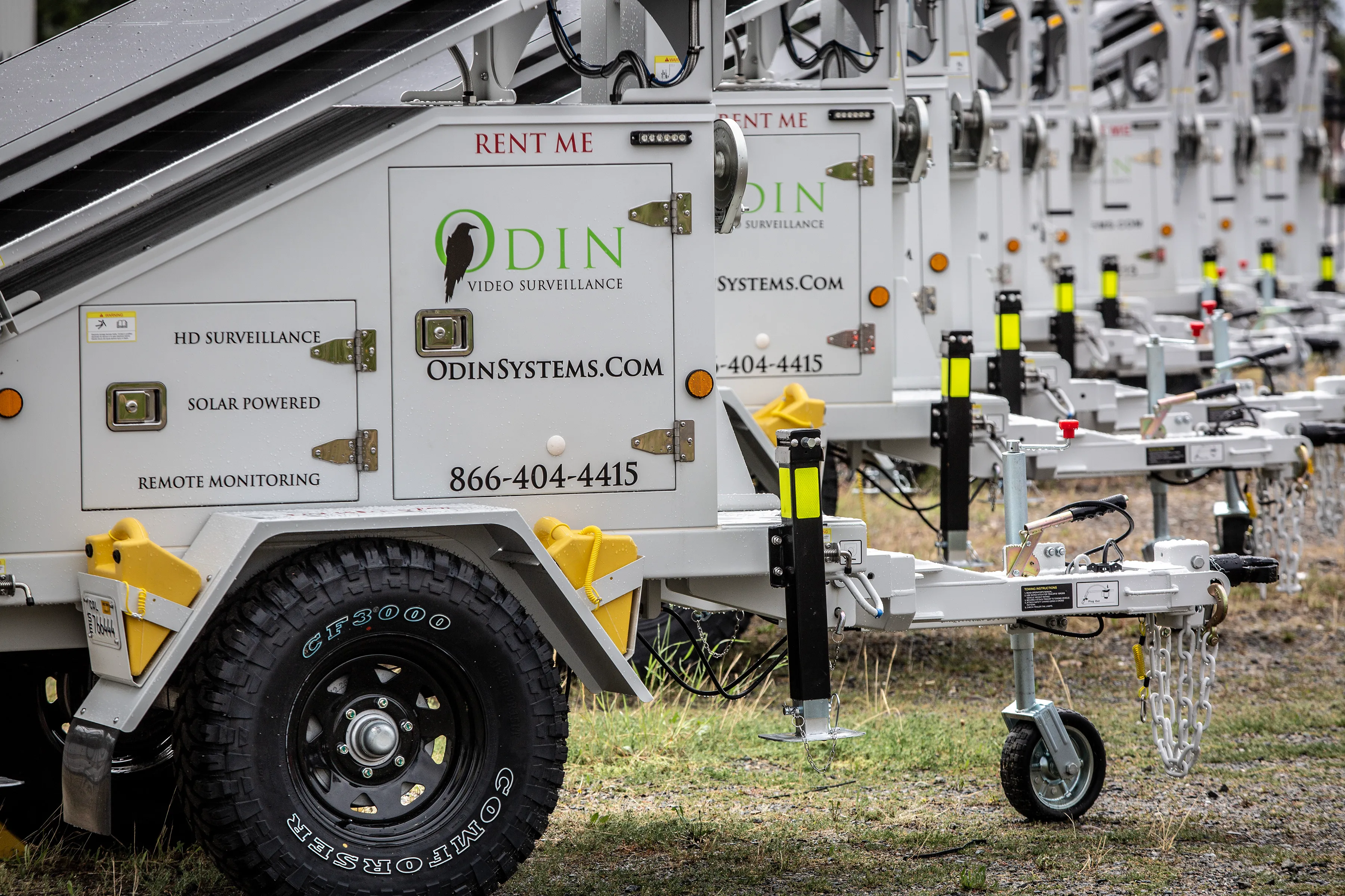 A fleet of Odin Systems solar-powered surveillance trailers lined up, each branded with the Odin Video Surveillance logo and marked HD Surveillance, Solar Powered, and Remote Monitoring.